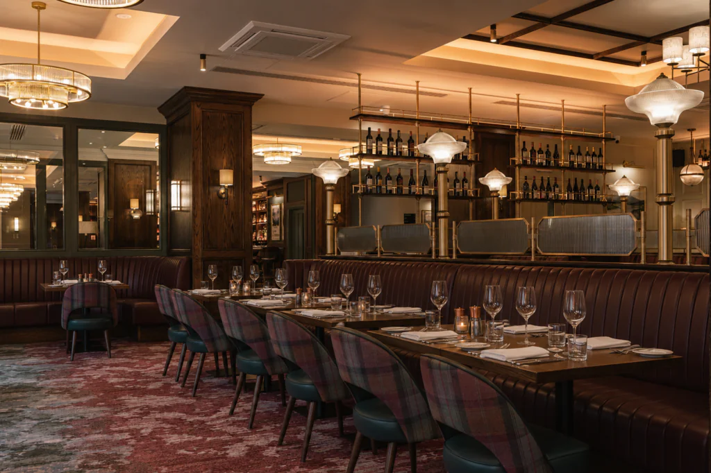 Carriage 4 Elegant restaurant interior with dark wood accents, upholstered seating, set tables with glassware, wine bottles on shelves, and warm ambient lighting.